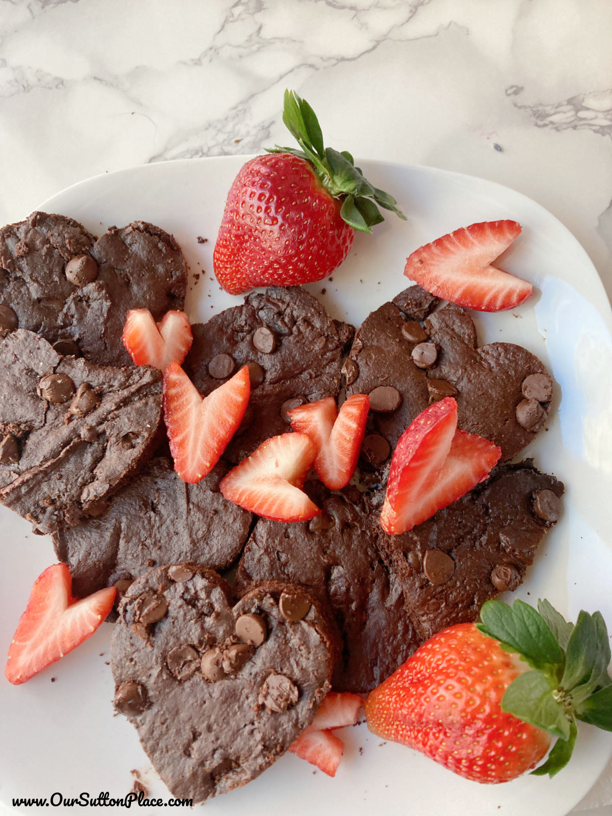 plate of heart-shaped brownie cookies with strawberries as garnish